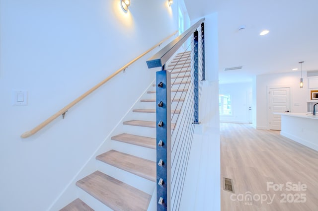 stairs featuring hardwood / wood-style flooring and sink