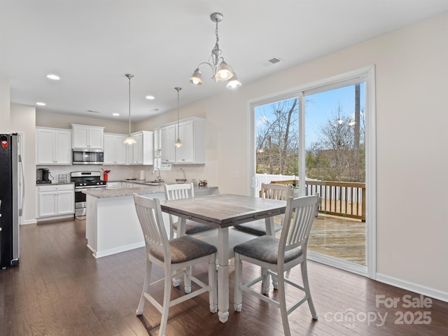 dining area featuring dark hardwood / wood-style flooring, a chandelier, and sink