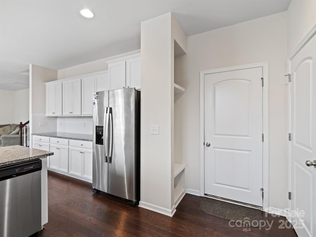 kitchen with white cabinets, light stone counters, stainless steel appliances, and dark wood-type flooring