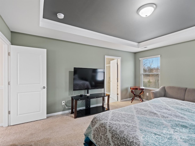 bedroom with a raised ceiling, light carpet, and connected bathroom