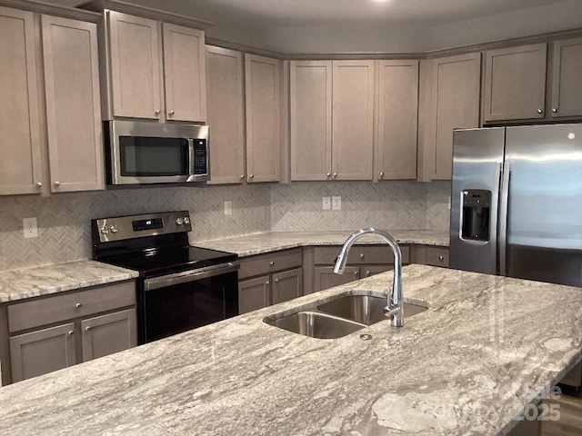 kitchen featuring light stone counters, sink, appliances with stainless steel finishes, and tasteful backsplash