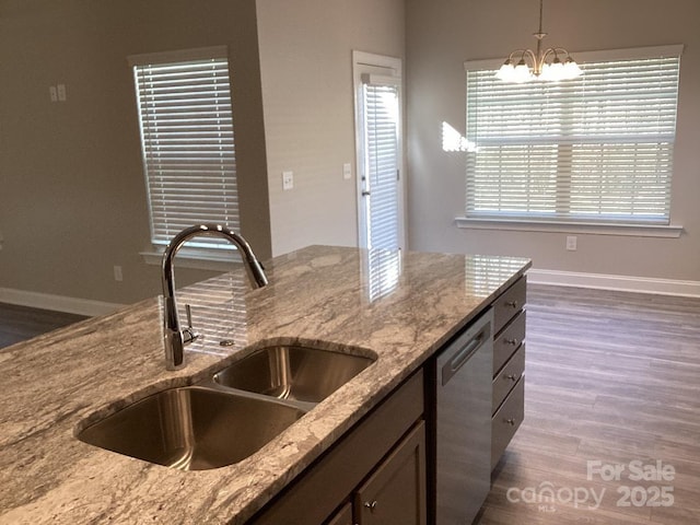 kitchen featuring dishwasher, sink, light stone counters, a chandelier, and decorative light fixtures