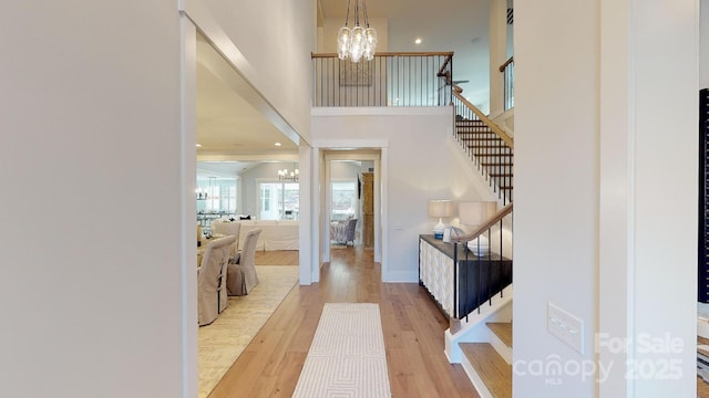 foyer entrance with a towering ceiling, a chandelier, and hardwood / wood-style flooring