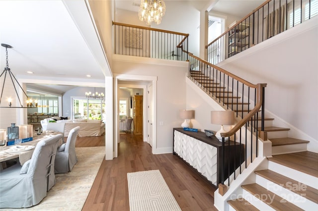 stairway with hardwood / wood-style floors and a notable chandelier