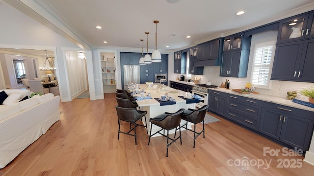 kitchen featuring stainless steel appliances, blue cabinetry, light wood-type flooring, a breakfast bar, and decorative light fixtures