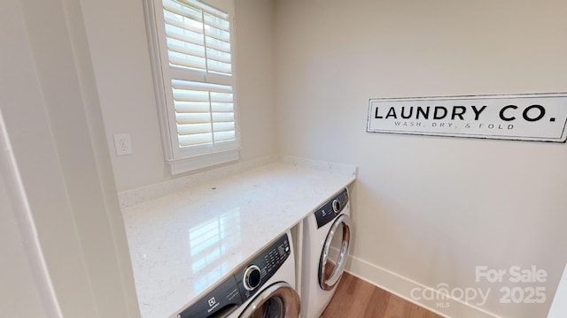 laundry area featuring washer and dryer and light hardwood / wood-style flooring