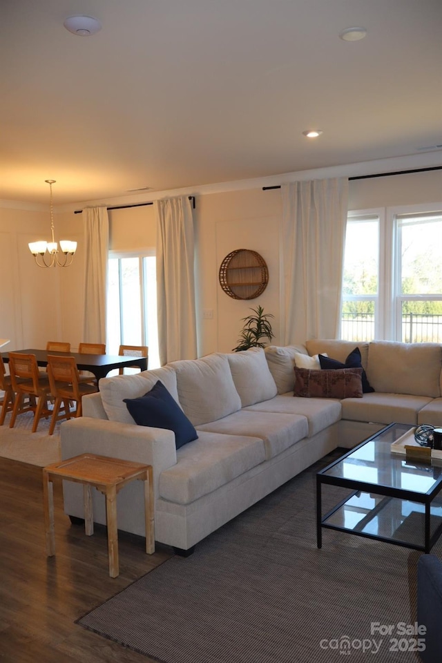 living area with recessed lighting, plenty of natural light, wood finished floors, and a notable chandelier