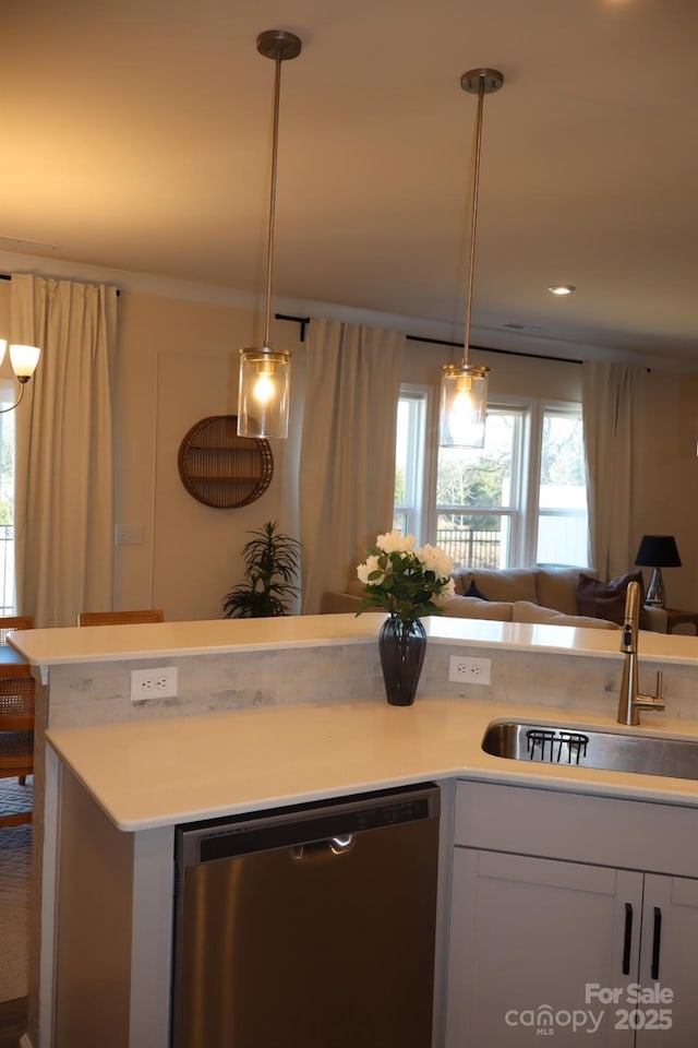 kitchen featuring dishwasher, light countertops, a sink, and pendant lighting