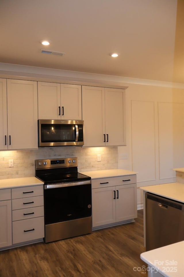 kitchen with stainless steel appliances, dark wood-type flooring, light countertops, and visible vents