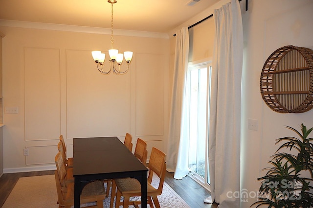 dining room with a notable chandelier, crown molding, a decorative wall, and dark wood-type flooring