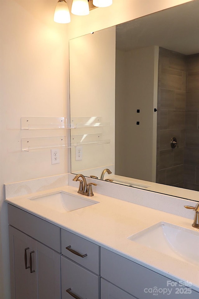 bathroom with double vanity, tiled shower, and a sink