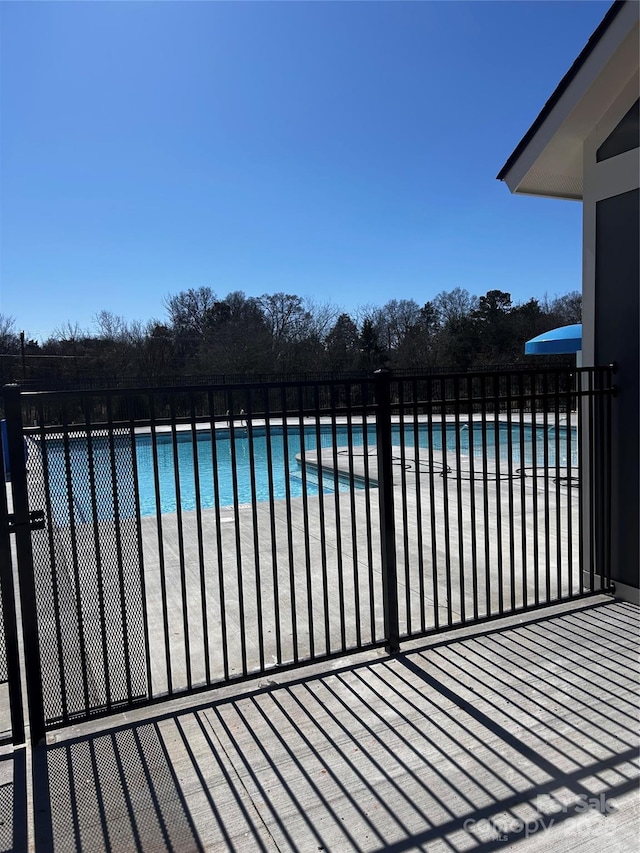 community pool with a water view and fence