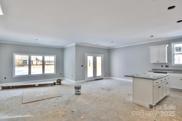 kitchen with a center island, light stone counters, a wealth of natural light, and white cabinetry