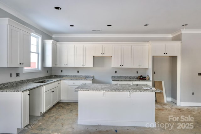 kitchen with crown molding, light stone countertops, a kitchen island, white cabinets, and sink