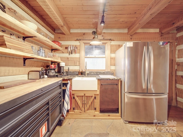 kitchen featuring stainless steel refrigerator, beamed ceiling, sink, track lighting, and wooden ceiling