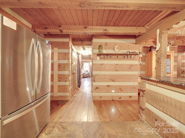 kitchen featuring wood ceiling, stainless steel fridge, and wood walls