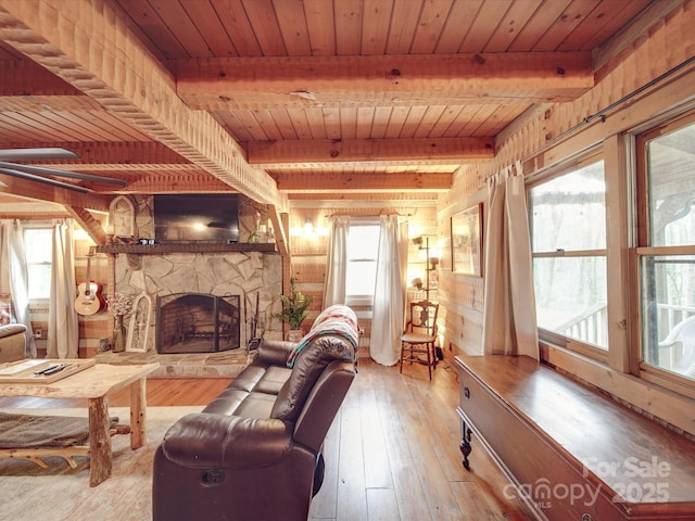 living room with a stone fireplace, wooden ceiling, beamed ceiling, and light wood-type flooring