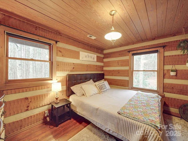 bedroom with hardwood / wood-style flooring, wood ceiling, and wood walls