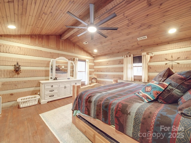 bedroom with vaulted ceiling with beams, light wood-type flooring, wooden ceiling, and wood walls