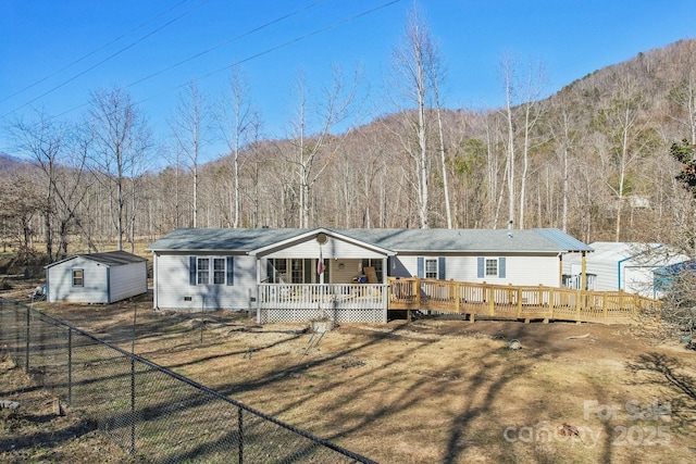 back of property featuring a storage shed, a yard, and a deck with mountain view