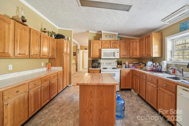 kitchen featuring sink, white appliances, ornamental molding, and a kitchen island