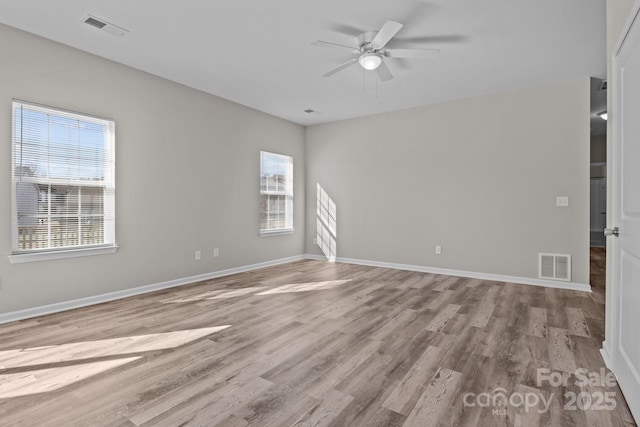 empty room featuring ceiling fan, light hardwood / wood-style floors, and a wealth of natural light