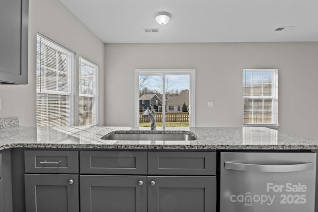 kitchen featuring gray cabinets, light stone countertops, and sink