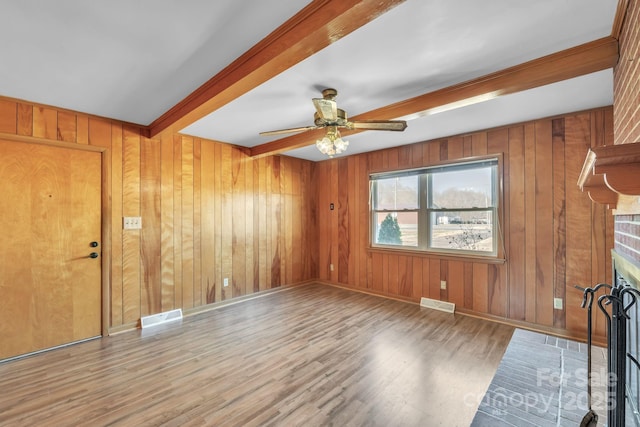 unfurnished living room with hardwood / wood-style flooring, ceiling fan, and wood walls