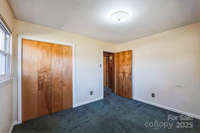 unfurnished bedroom with dark colored carpet and a closet