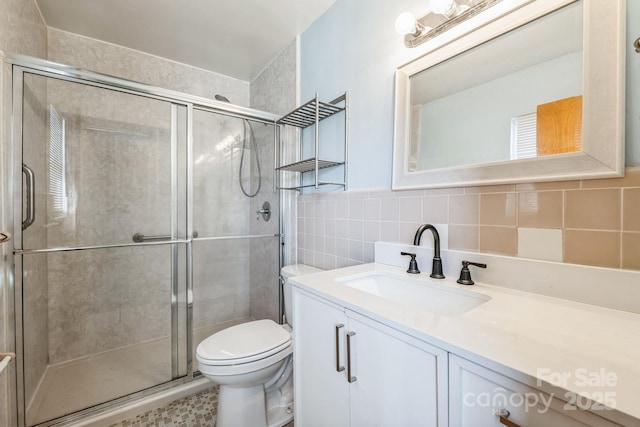 bathroom featuring tasteful backsplash, vanity, an enclosed shower, and toilet