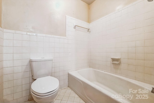 bathroom featuring toilet, tile patterned flooring, tile walls, and a tub