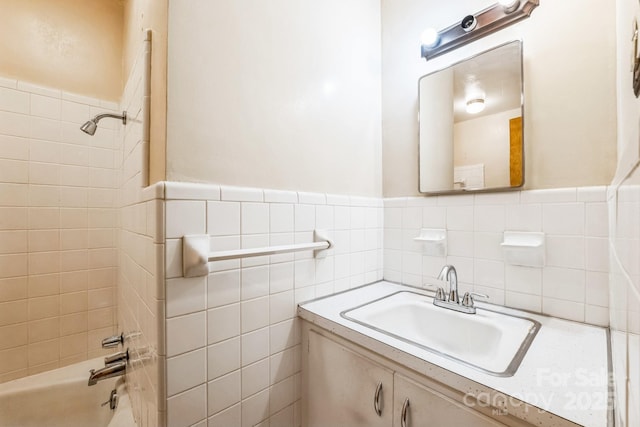 bathroom featuring tiled shower / bath, tile walls, and vanity