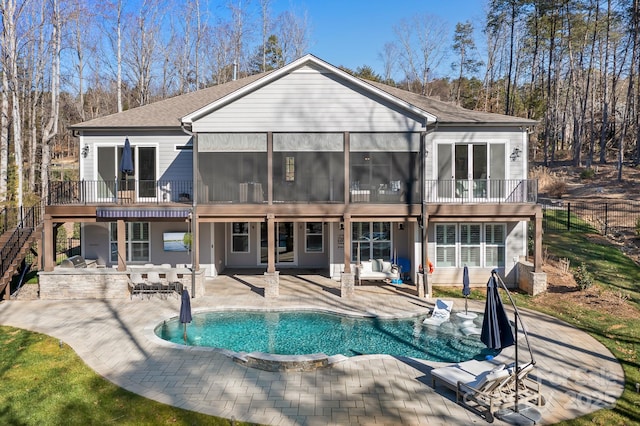 rear view of house featuring a sunroom, a balcony, and a patio