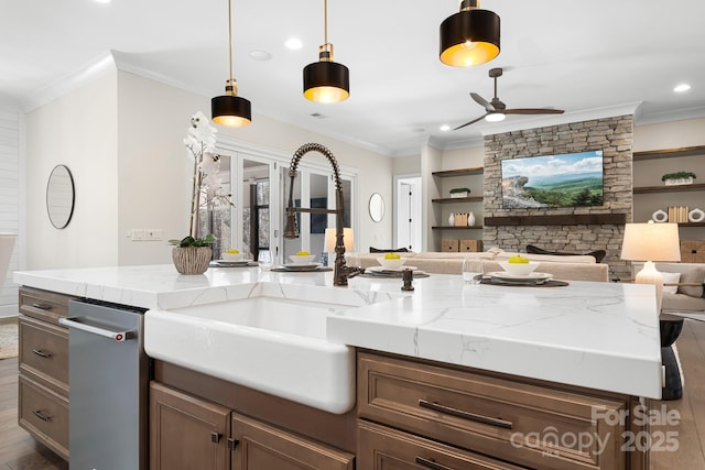 kitchen with sink, ceiling fan, light stone counters, and hanging light fixtures