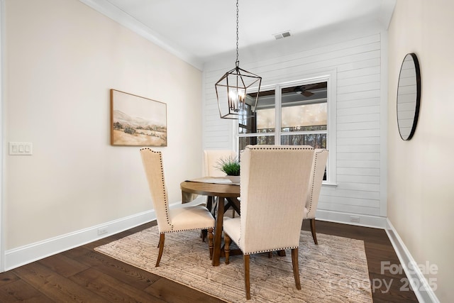 dining area with crown molding, dark wood-type flooring, and a chandelier