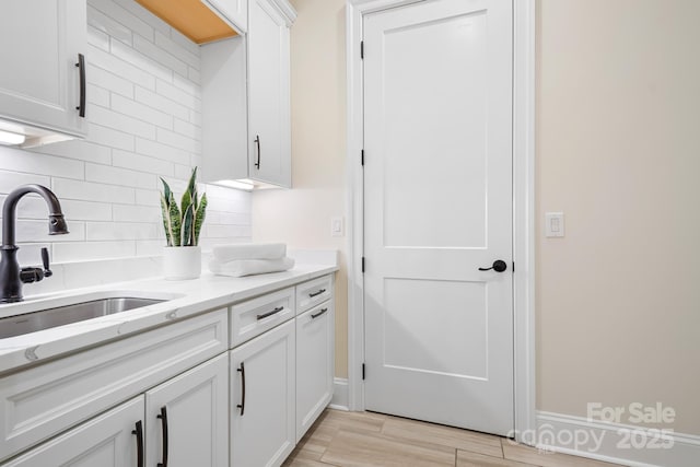 kitchen featuring white cabinets, light stone countertops, sink, and tasteful backsplash