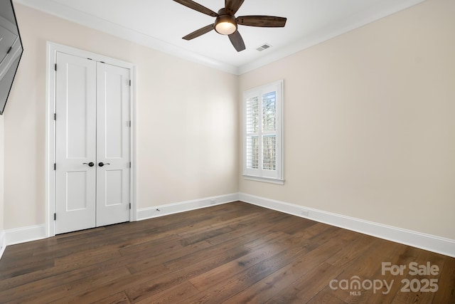 unfurnished bedroom with ceiling fan, a closet, dark hardwood / wood-style floors, and ornamental molding