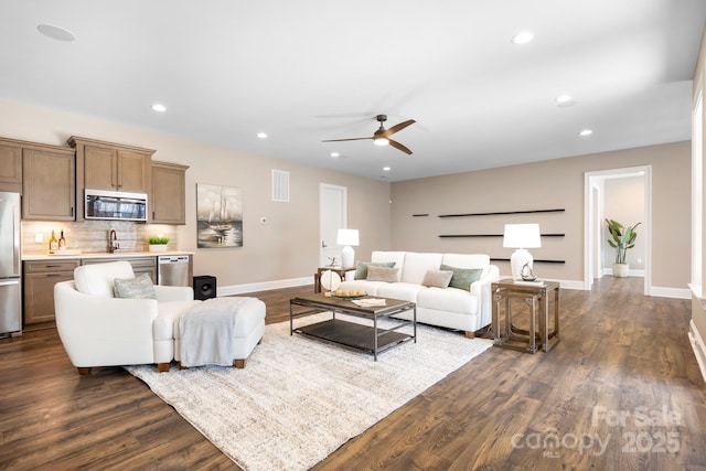 living room featuring ceiling fan, sink, and dark wood-type flooring