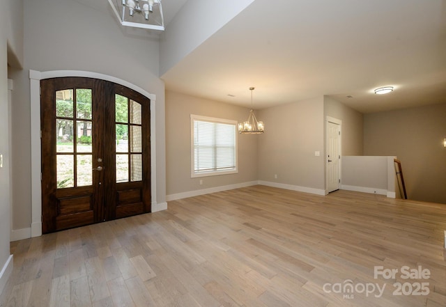 foyer with a chandelier, light hardwood / wood-style floors, and french doors