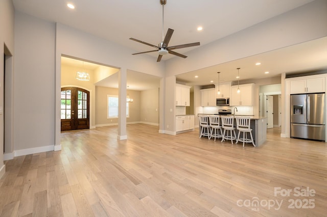 kitchen with appliances with stainless steel finishes, french doors, a breakfast bar, a kitchen island with sink, and white cabinets