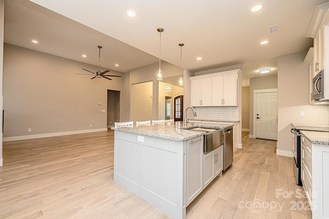 kitchen featuring ceiling fan, white cabinetry, stainless steel appliances, and a kitchen island with sink