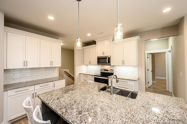 kitchen featuring appliances with stainless steel finishes, decorative light fixtures, and white cabinetry