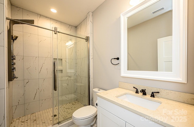 bathroom featuring vanity, a shower with shower door, and toilet