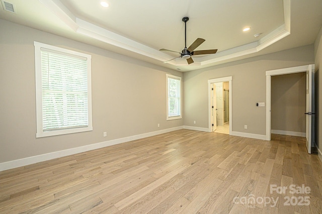 unfurnished bedroom featuring ceiling fan, light hardwood / wood-style flooring, connected bathroom, and a tray ceiling