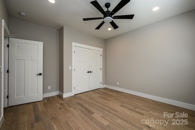 unfurnished bedroom with ceiling fan, a closet, and hardwood / wood-style flooring