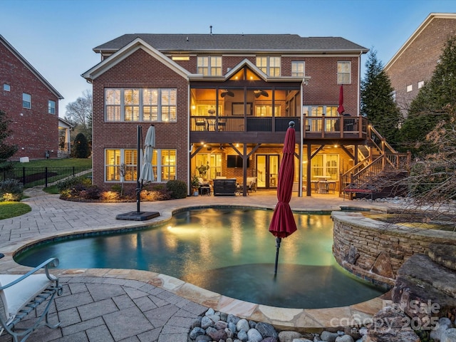 back house at dusk featuring a pool side deck, an outdoor living space, sink, and a patio