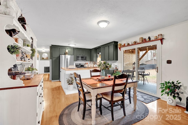 dining room with a textured ceiling and light hardwood / wood-style flooring