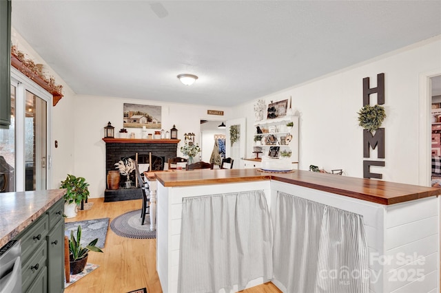 kitchen featuring light hardwood / wood-style floors, a brick fireplace, and butcher block countertops