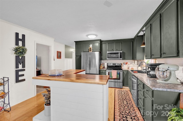 kitchen with sink, stainless steel appliances, green cabinetry, and light hardwood / wood-style floors