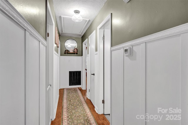 hall with hardwood / wood-style floors and a textured ceiling